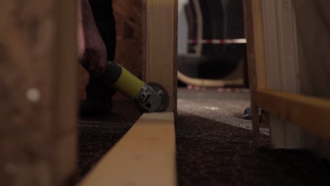low angle shot of a worker using an angle grinder to cut through a wooden beam