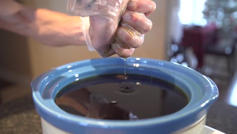 person squeezing excess liquid from teabag unto pot - medical marijuana - close up shot