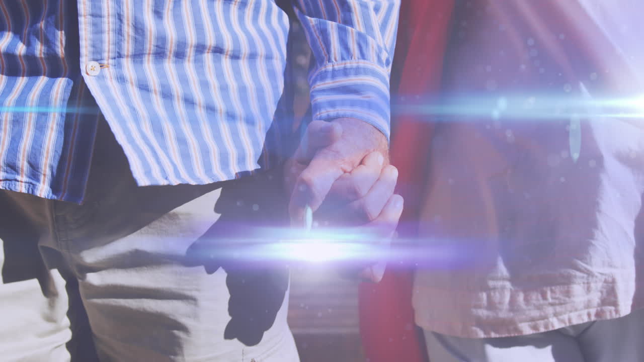 손을 잡고 공원에서  ⁇ 고 있는 노인 부부의 중간 부분을 가로질러 움직이는 빛의 애니메이션