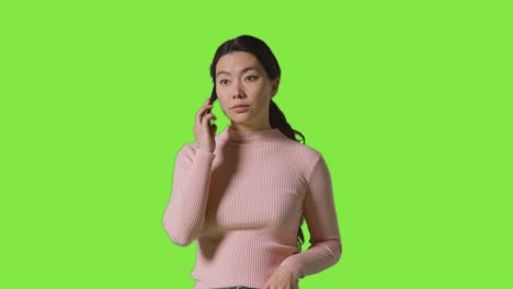 studio shot of woman answering mobile phone against green screen 1