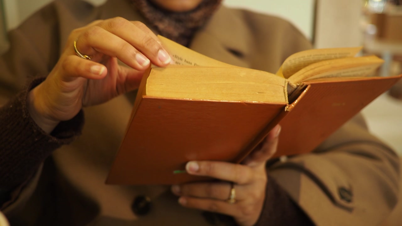 Close-up of a Person Reading an Old Book and Turning Pages
