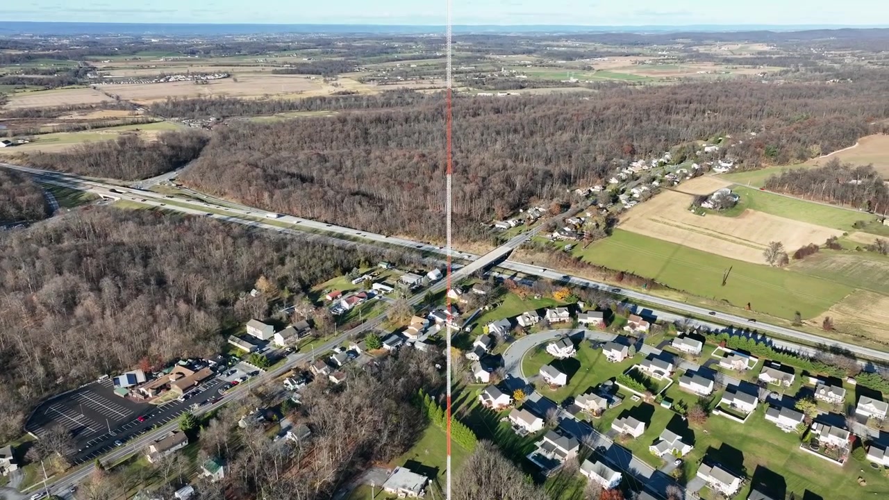 Moderno quartiere americano con case di lusso in un'area suburbana. Giornata di sole in autunno con autostrada trafficata. Torre di trasmissione al centro dell'area residenziale. Ampia ripresa aerea con inclinazione verso l'alto.