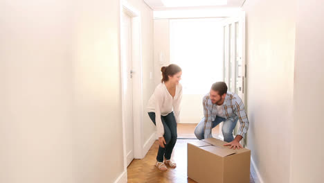 Attractive-couple-carrying-cardboard-box-inside