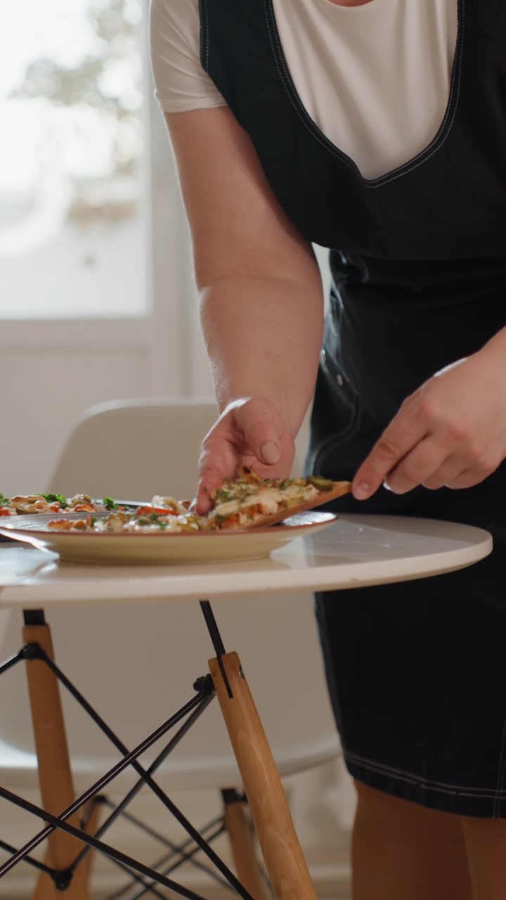 Torso e mani di una persona che sistema tartine monoporzione su un tagliere di legno, trasferendo i pezzi su un piatto con una spatola e le dita, mostrando un posizionamento preciso, un gesto di servizio e cibo raffinato.
