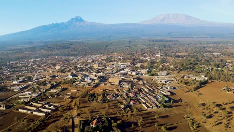 Amanecer:-Paisaje-De-Kenia-Con-Un-Pueblo,-Kilimanjaro-Y-El-Parque-Nacional-De-Amboseli---Seguimiento,-Vista-Aérea-De-Drones