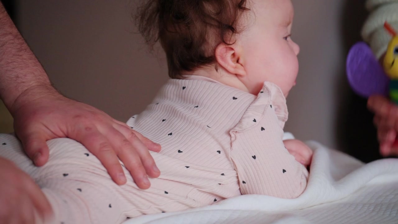 Neonato sdraiato a pancia in giù mentre un adulto stabilizza il corpo del bambino e un'altra persona muove un giocattolo colorato nelle vicinanze per stimolare il coinvolgimento.