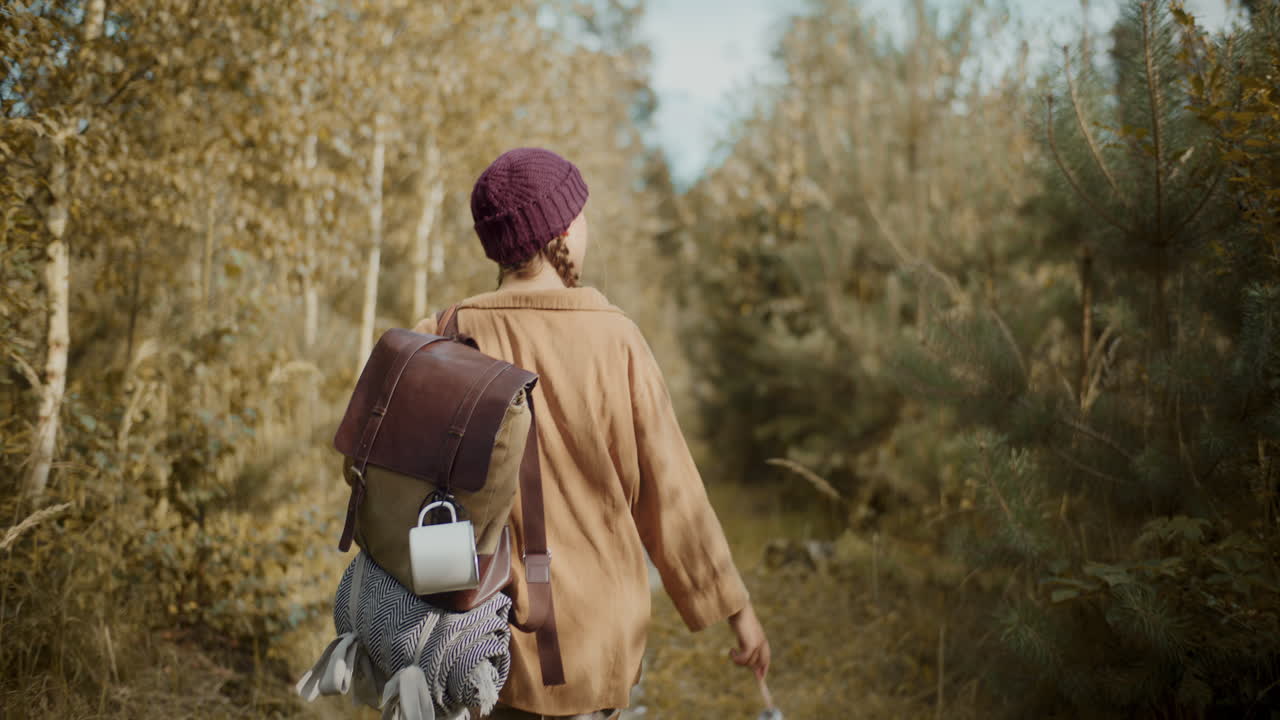 Female tourist with backpack and bottle walking in forest