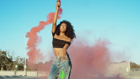 una mujer joven bailando afuera con una granada de humo al atardecer en el garaje del techo