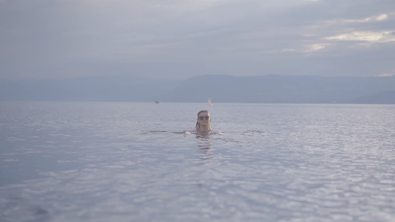 산악 호수에서 수영하는 매력적인 소녀