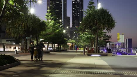 people walking through a lit urban park at night