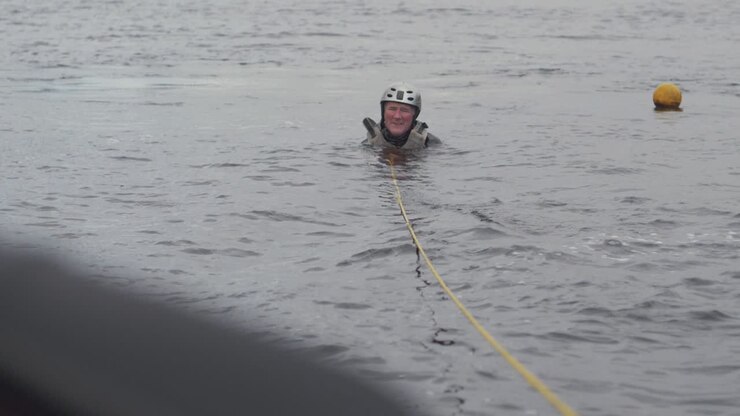 Water skier sits in water beside buoy slalom course