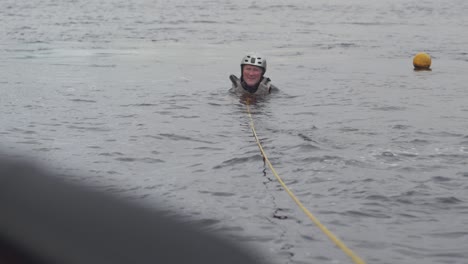 water skier sits in water beside buoy slalom course