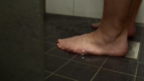 low angle view of defocused male feet in shower, focus on foreground