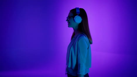 young woman with headphones listening to music on a vibrant purple background