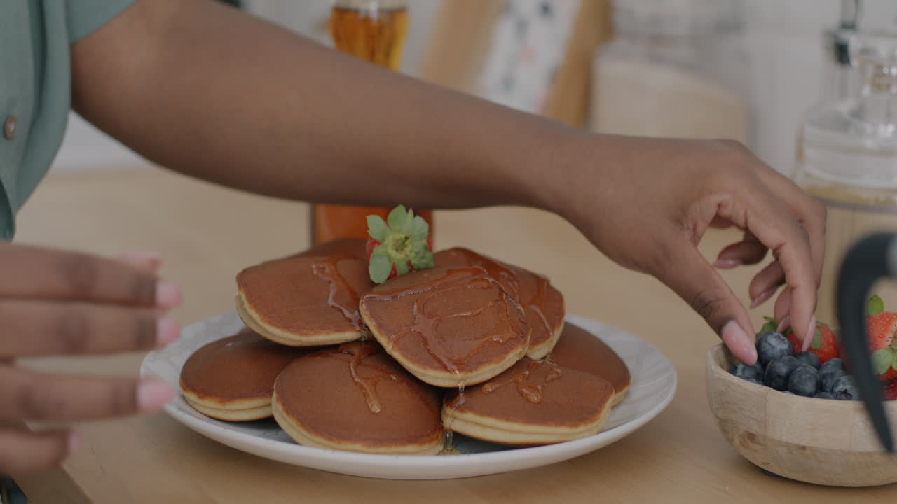 Woman enjoying pancakes with honey and berries