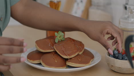 woman enjoying pancakes with honey and berries