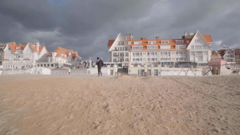 senior man walking on the beach of coastal village de haan in belgium during windy autumn day