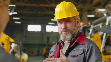 senior factory worker talking with colleague