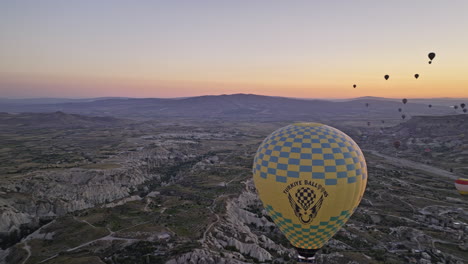 Göreme-Turquía-Aérea-V48-Vista-Panorámica-De-Gran-Altitud-Sobrevuelo-Antiguo-Pueblo-Que-Captura-El-Paisaje-Surrealista-Del-Amanecer-Con-Globo-Aerostático-Y-Terreno-De-Formaciones-Rocosas---Filmado-Con-Cine-Mavic-3---Julio-De-2022