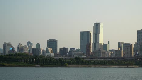 korean trade tower and many skyscrapers and high buildings in sunset light from han river waterfront, cars traffic on