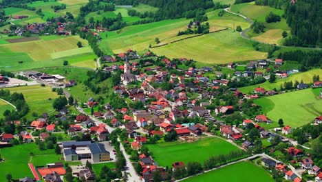 drone footage of st. peter am kammersberg, a charming austrian village nestled in rolling green hills and surrounded by forested mountains