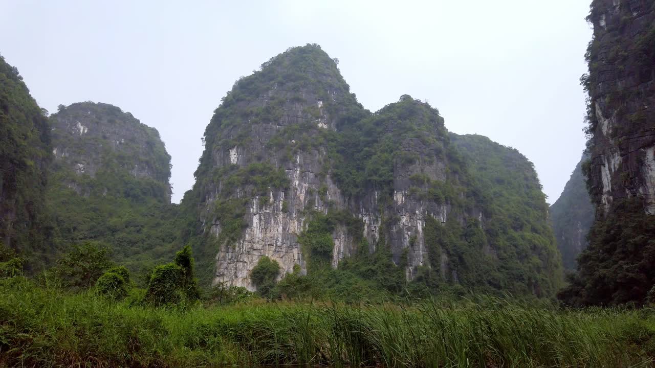 tam coc paisaje de montañas kársticas de piedra caliza en la provincia de ninh binh vietnam visto desde un bote en el río de día, dolly right shot