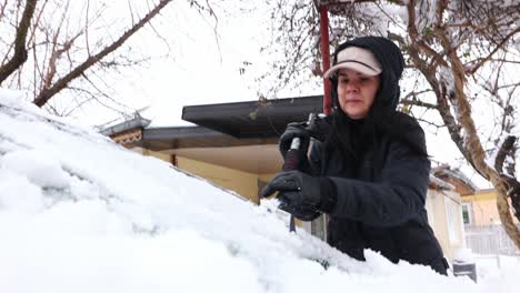 Close-Up-Of-Woman-Cleaning-Snow-From-Car-Using-An-Ice-Scraper
