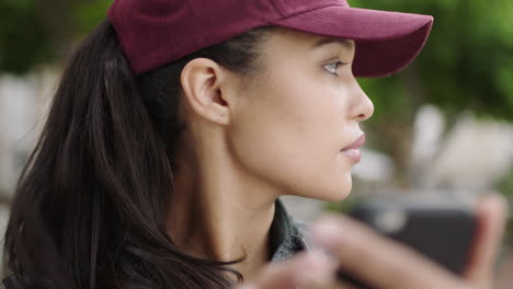 retrato en primer plano de una hermosa mujer de raza mixta turista que parece perdida usando un teléfono inteligente navegando en línea usando un sombrero en la ciudad urbana