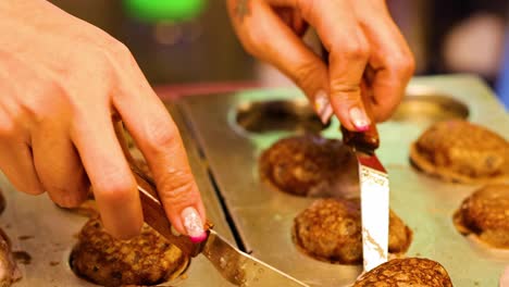 close-up of hands using a knife to shape cookies on a baking tray.
