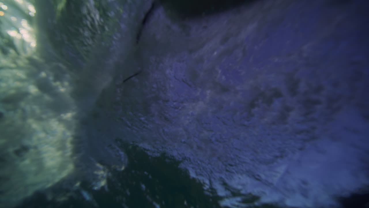 paseos en longboard a través de la superficie de la ola submarina en el océano