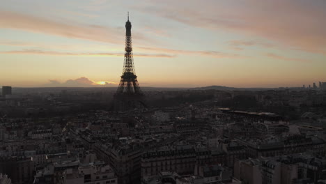 Forwards-fly-above-buildings-and-streets-in-urban-borough.-Silhouette-of-Eiffel-Tower-against-colourful-twilight-sky.-Paris,-France