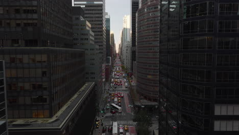 Fly-above-wide-avenue-with-heavy-traffic.-Street-surrounded-by-modern-skyscrapers.-Manhattan,-New-York-City,-USA