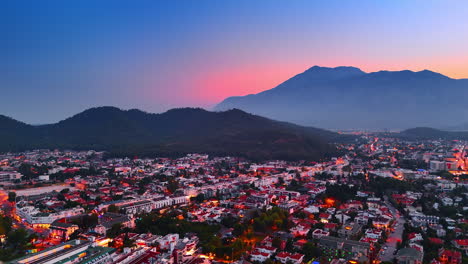 city lights switched on in the cityscape of resort kemer, turkey. drone footage over the scenery at sunset. pink sky among the rocks silhouettes at backdrop