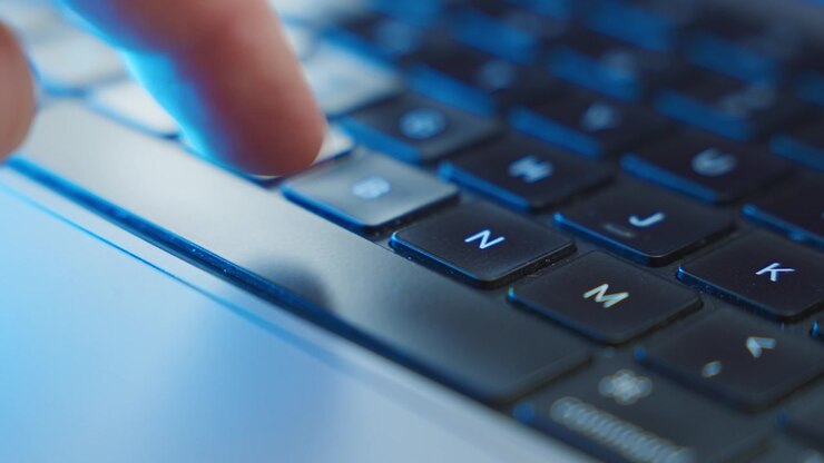 Close up on finger pressing the space bar key on laptop computer keyboard in dark office room. Mysterious atmosphere cyber hacker or criminal or programmer clicking button to start process algorithm