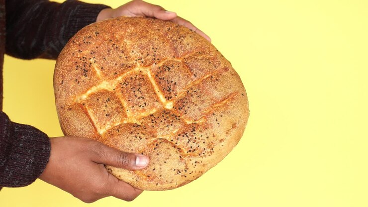 Close-up of a person holding a loaf of fresh baked bread