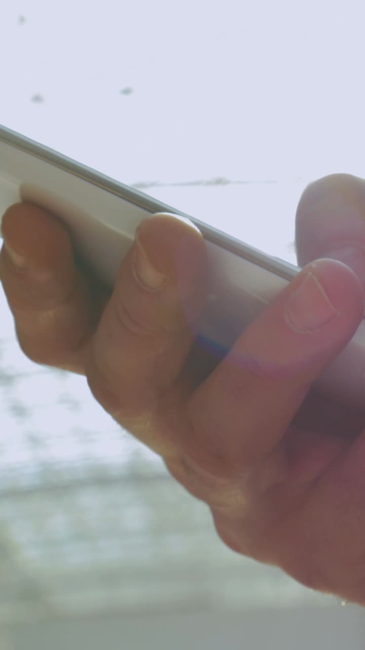 Hand holding a phone at the beach