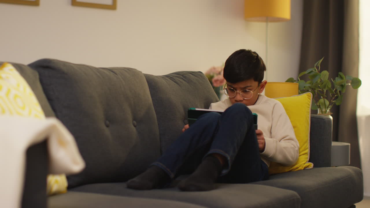 Young Boy Sitting On Sofa At Home Playing Games Or Streaming Onto Digital Tablet 6