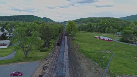 Una-Vista-Aérea-De-Una-Carretera-Ferroviaria-De-Carbón-De-Vía-Estrecha-Abandonada-Con-Tolvas-Oxidadas-Y-Vagones-De-Carga-Y-Un-Edificio-De-Apoyo-Que-Comienza-A-Restaurarse