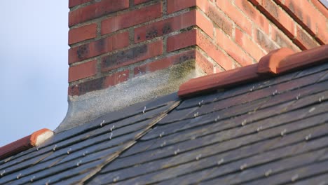 repaired brick chimney and slate roof tiles secured with nails wide shot