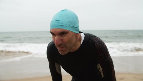 tired male swimmer standing on beach