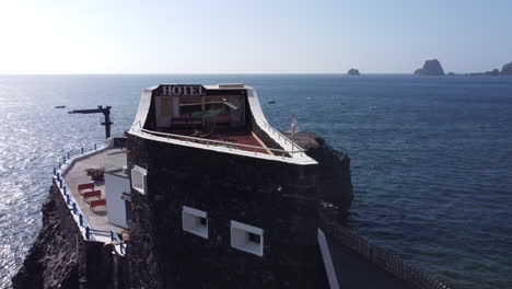 a small hotel puntagrande overlooking the calm sea on a rocky plateau of lava origin in sunny and windy weather, el hierro - drone shot