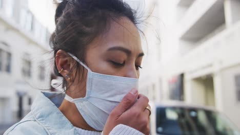 Mixed-race-woman-coughing-on-her-medical-coronavirus-mask