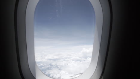 Dolly-En-Cámara-Lenta-Tira-De-La-Ventana-De-Un-Avión-Mientras-Está-En-Vuelo-Con-Un-Bonito-Cielo-Azul-Y-Nubes-Blancas