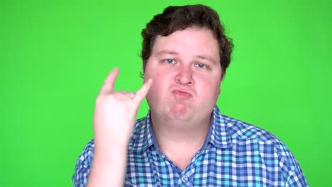 portrait of fat man rocker gesturing with hand and looking at camera against green background.