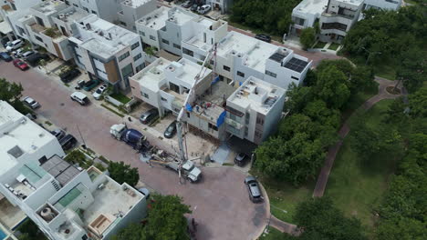 tilt down drone shot of a concrete pump pouring cement to make the tile of a house with several workers spreading the material