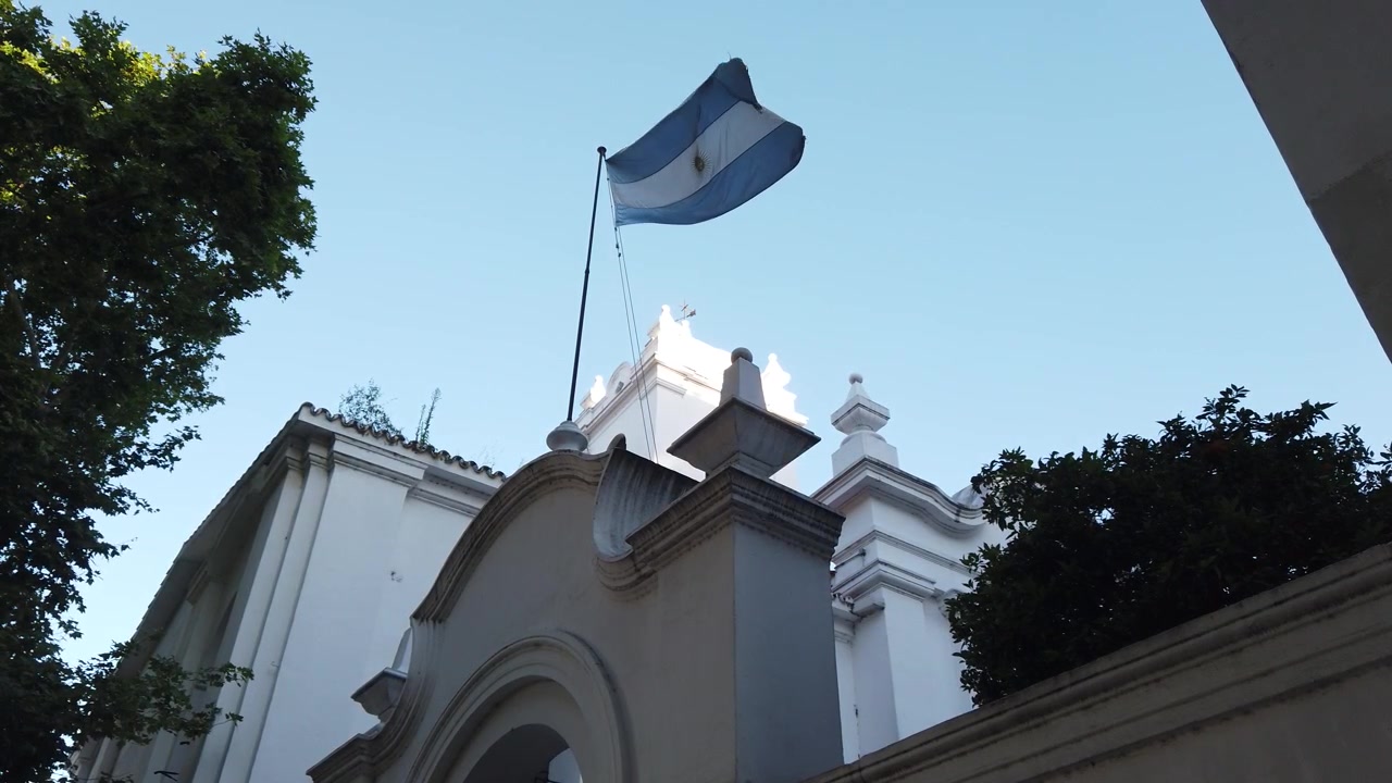 Edificio coloniale del Cabildo con bandiera argentina che sventola nello skyline primaverile, ripresa dal basso.