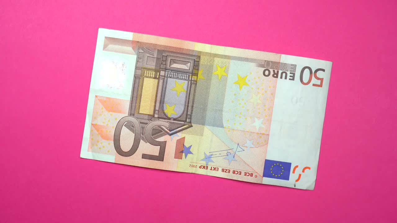 Dönen pembe bir arka plan üzerinde hızla dönen 50 avro