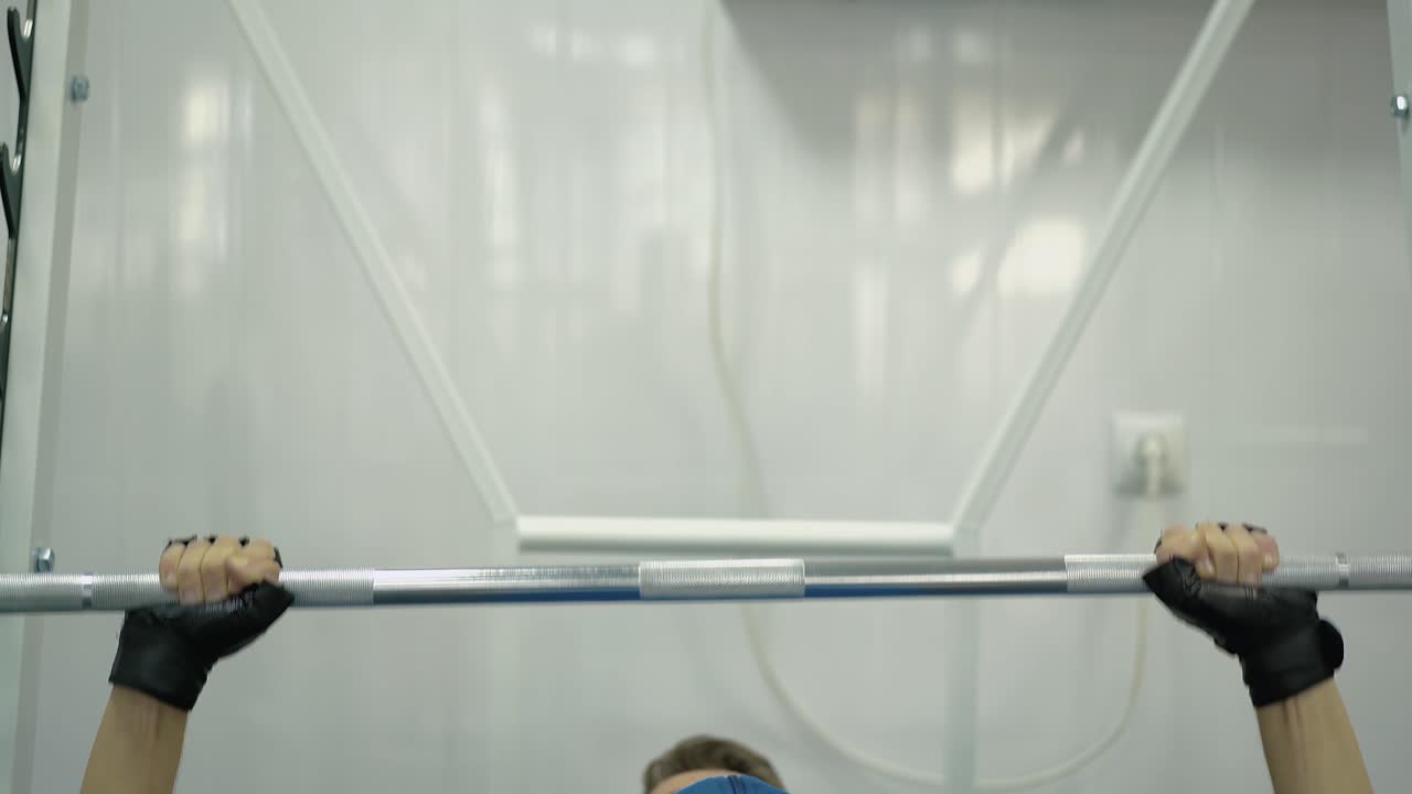 한 남자가 벤치 프레스를 수행합니다. 장애인들을 위한 스포츠 홀에서 2개의 운동 수업이 열립니다.