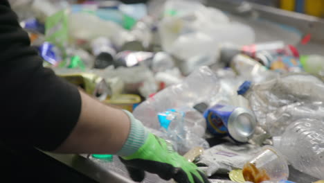 personas clasificando botellas de plástico y latas de aluminio en una cinta transportadora en una planta de reciclaje
