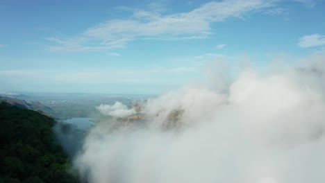 forward drone shot through fog clouds, over forest mountains towards a distant lake of western ghats